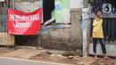 Seorang anak berdiri dekat poster protes warga terhadap pembangunan flyover di kawasan Tanjung Barat, Jakarta, Rabu (15/7/2020). Dalam poster protes tersebut, warga menuntut agar pembayaran pelunasan pembebasan lahan segera diselesaikan secara serentak. (Liputan6.com/Immanuel Antonius)