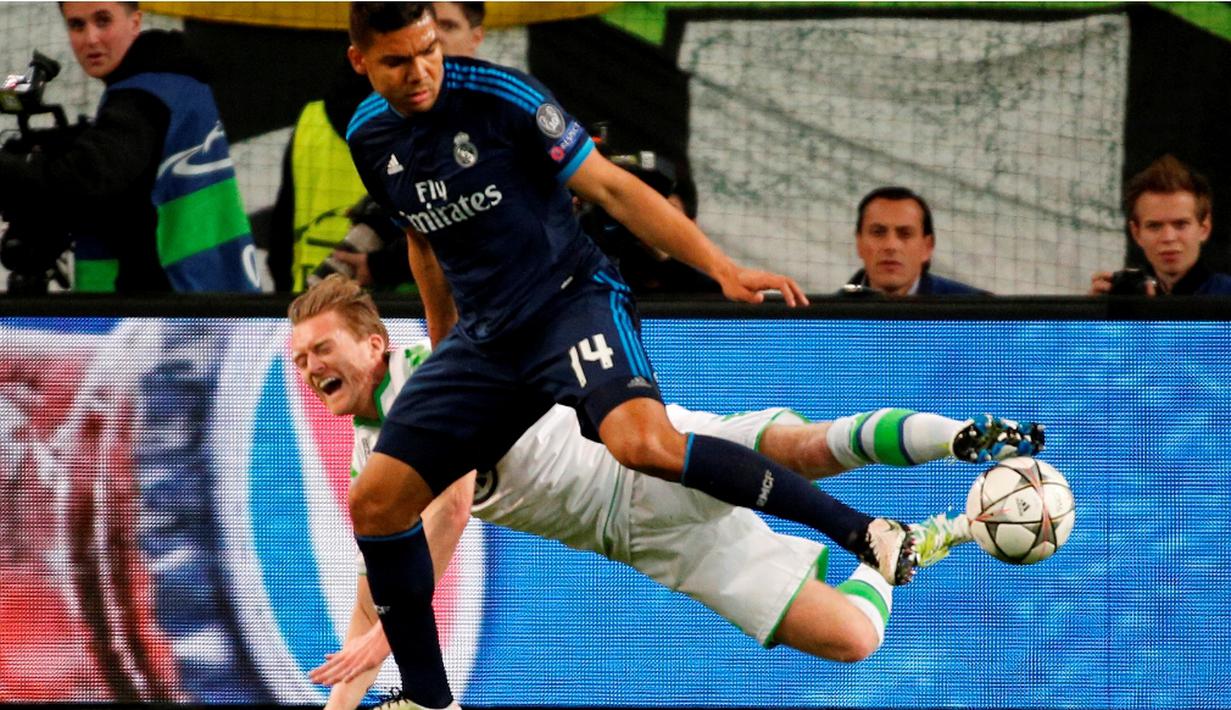 Perebutan bola antara pemain Wolfsburg, Andre Schuerrle, dan pemain Real Madrid, Casemiro, pada leg pertama perempat final Liga Champions di Volkswagen Arena, Wolfsburg, Kamis (7/4/2016) dini hari WIB. (AFP/Odd Andersen)