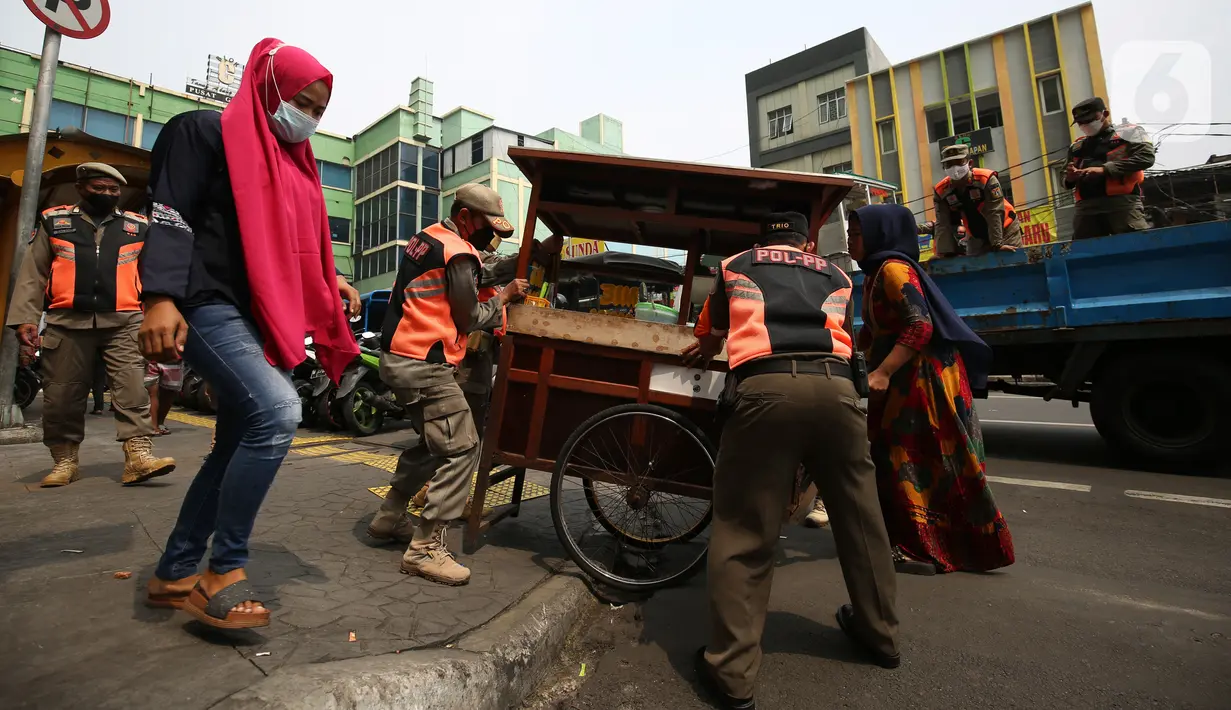 Petugas Satpol PP membawa gerobak pedagang kaki lima (PKL) yang bandel berjualan di trotoar Pasar Tanah Abang, Jakarta, Senin (4/10/2021). Penertiban dilakukan untuk memberikan kenyamanan dan keamanan bagi para pengguna jalan yang melintas di trotoar tersebut. (Liputan6.com/Angga Yuniar)