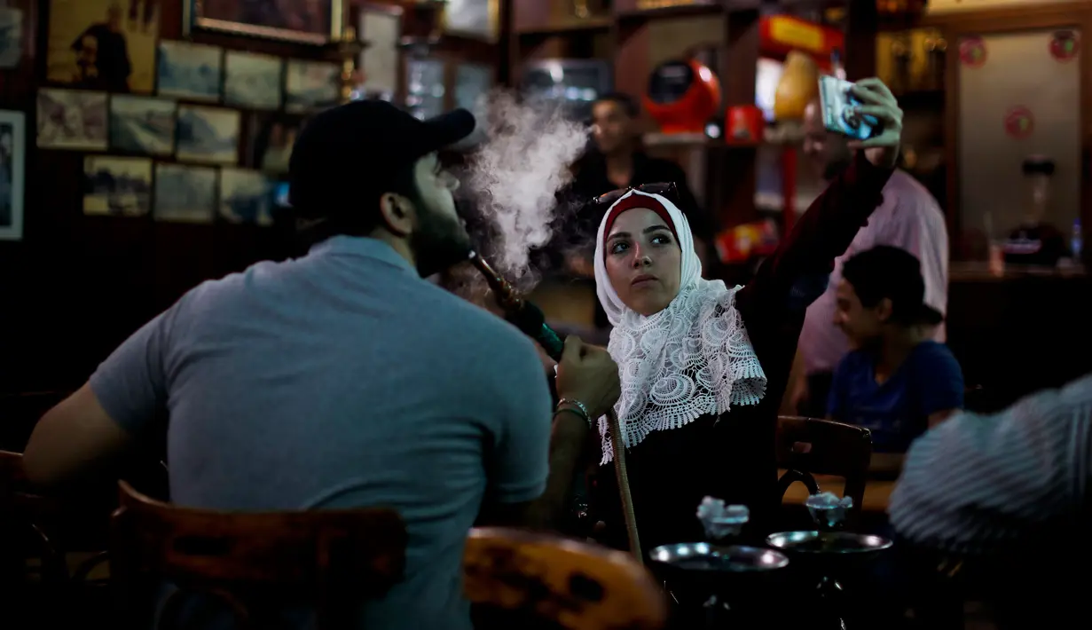 Seorang remaja wanita Suriah berselfie di Kafe al-Nafurah di kota tua Damaskus, Suriah, (14/7). Populasi di Kota ini diperkirakan sekitar 3.67 juta jiwa. (AP Photo / Hassan Ammar)