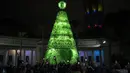 Orang-orang menggunakan ponsel mereka untuk memfilmkan upacara penyalaan pohon Natal yang terbuat dari botol plastik daur ulang di Caracas, Venezuela, Selasa (13/12/2022). Pohon Natal yang dibuat dari sekitar 15.000 botol plastik daur ulang ini diinisiasi oleh organisasi nirlaba dan non-pemerintah Oko Spire dan kolaborator. (Yuri CORTEZ / AFP)