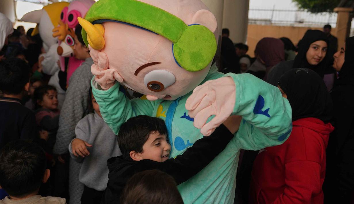 Seorang anak memeluk seseorang yang mengenakan kostum saat para sukarelawan menyiapkan bingkisan makanan dan manisan Idulfitri untuk keluarga pengungsi yang merayakan hari raya jauh dari rumah mereka, di sebuah universitas negeri yang diubah menjadi tempat penampungan setelah serangan udara Israel di Beirut, Lebanon, Jumat 20 Maret 2026. Perayaan Hari Raya Idulfitri 1447 Hijriah di sebuah Universitas Negeri yang diubah menjadi tempat penampungan warga setelah serangan udara Israel di Beirut, Lebanon, berlangsung penuh keceriaan. (AP Photo/Hassan Ammar)