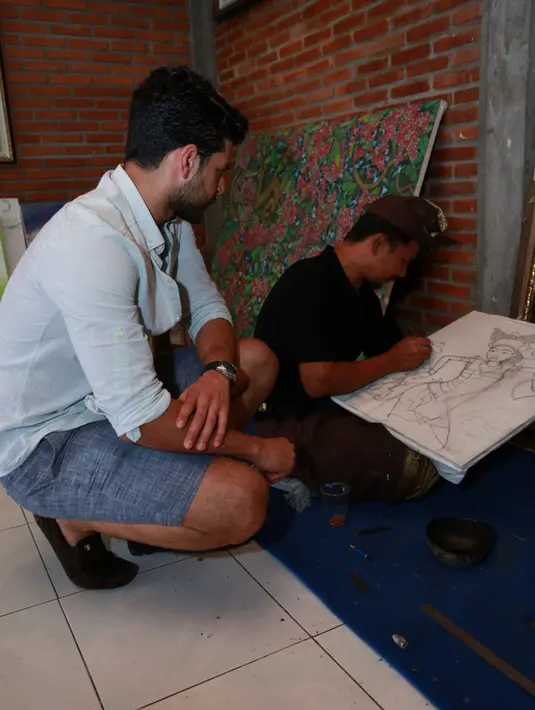 Emre Kivilcim nampak serius melihat kegiatan melukis yang dilakukan oleh pria Bali ini di Galeri Semar Kuning, Ubud, Bali. (Deki Prayoga/Bintang.com)