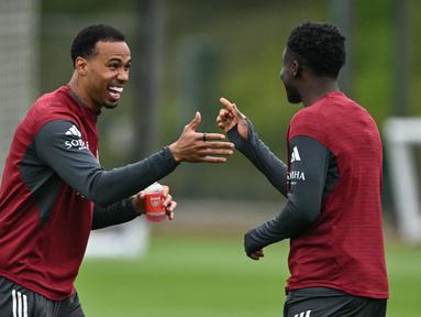 Pemain Arsenal, Gabriel Magalhaes (kiri) tampak sedang bercanda dengan rekan satu timnya pada sesi latihan jelang leg kedua semifinal Liga Champions melawan Atletico Madrid di Emirates Stadium, London, Rabu (6/5/2026) dini hari WIB. (AFP/Glyn Kirk)