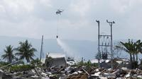 Helikopter BNPB menyemprotkan cairan disinfektan ke kawasan terdampak likuifaksi di Petobo dan Balaroa, Palu, Sulawesi Tengah, Kamis (18/10). Likuifaksi adalah fenomena yang terjadi ketika tanah jenuh atau agak jenuh kehilangan kekuatan. (Yusuf Wahil/AFP)
