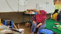 Seorang ibu di antara peralatan memasak di dapur umum yang didirikan secara swadaya di Kelurahan Gadang, Kota Malang, demi membantu warga yang sedang isolasi mandiri karena Covid-19 (Liputan6.com/Zainul Arifin)