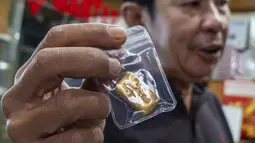 Seorang pedagang emas menunjukkan batangan emas kepada pelanggan di sebuah toko emas di Jakarta pada Jumat 29 Mei 2026. (BAY ISMOYO/AFP)