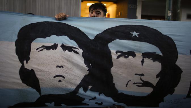 Penggemar berdiri di belakang spanduk bergambar Diego Maradona dan revolusioner Marxis Ernesto 