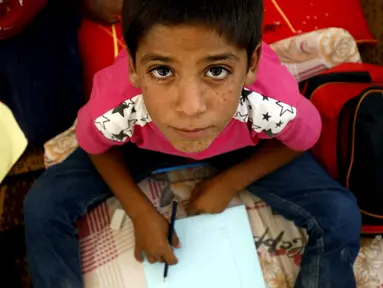  Ekspresi seorang anak pengungsi saat mengikuti kegiatan belajar di sebuah kamp di Ain Issa, Suriah (22/8). Meski belajar di dalam tenda pengungsian, anak-anak tetap antusias mengikuti hari pertama tahun ajaran baru sekolah. (AFP Photo/Delil souleiman)