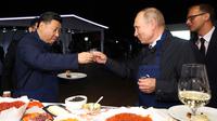 Presiden Rusia Vladimir Putin (kanan) dan Presiden China Xi Jinping (kiri) bersulang vodka saat menyantap pancake buatan bersama di sela acara Eastern Economic Forum di Vladivostok, Rusia, Selasa (11/9). (Sergei Bobylev/TASS News Agency Pool Photo via AP)