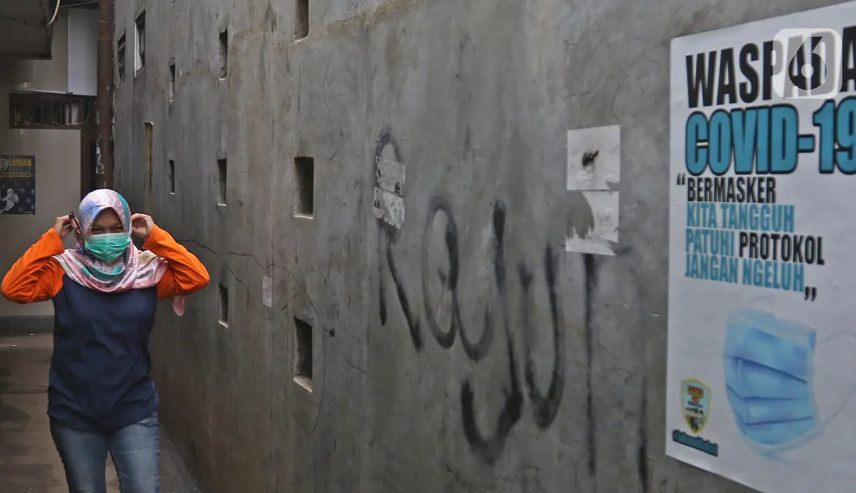 Seorang ibu melintas dekat poster Waspada Covid saat penerapan mikro lockdown RT 006 RW 01, Gandaria Selatan, Cilandak, Jakarta, Selasa (22/6/2021). Pemprov DKI menerapkan mikro lockdown di kampung itu lantaran adanya 17 warga yang positif Covid-19. (Liputan6.com/Herman Zakharia)