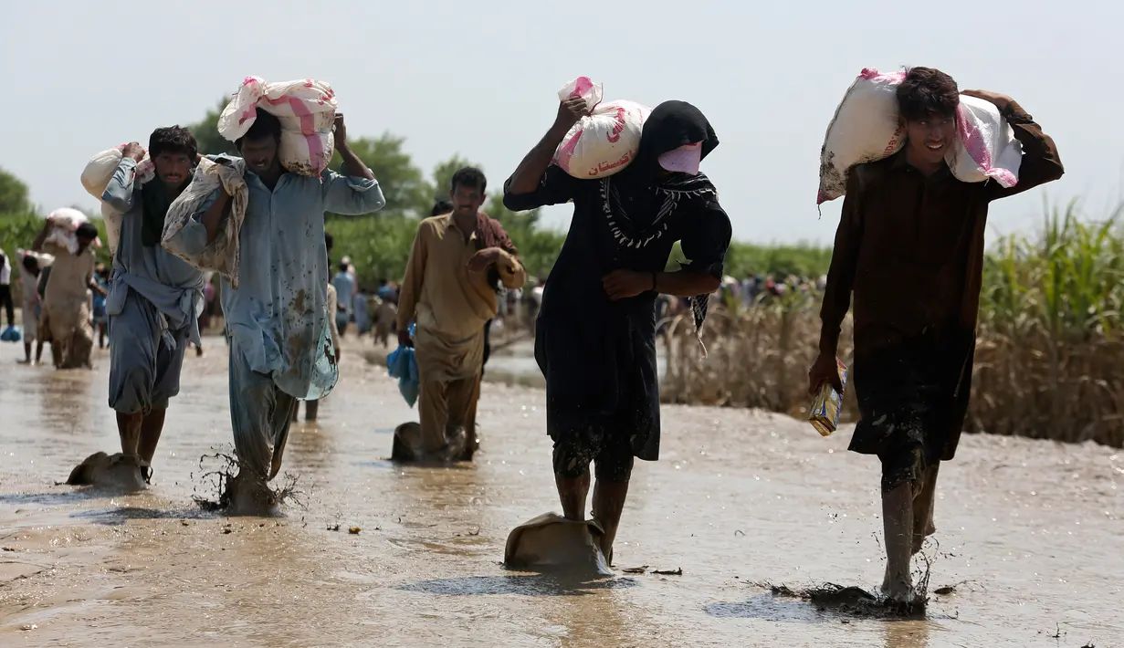 Korban banjir saat menerima bantuan Yayasan Edhi di Distrik Ghotki, Sindh Pakistan, Rabu (7/9/2022).Perkiraan menunjukkan banjir telah menyebabkan setidaknya US$ 10 miliar kerusakan di Pakistan, dan banyak orang menghadapi kekurangan makanan yang serius. Hampir setengah dari tanaman negara telah hancur. (AP Photo/Fareed Khan)