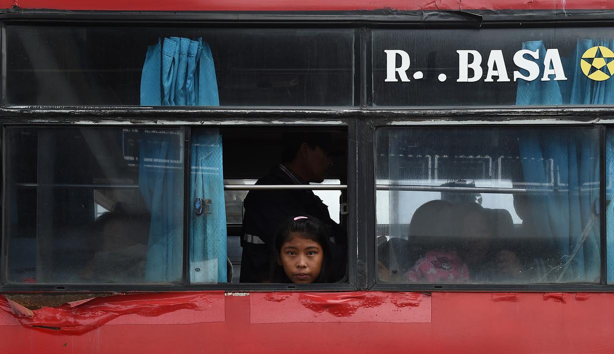 Seorang gadi sberada di dalam bus usai dievakuasi dari Pulau Sebesi, di Pelabuhan Bakauheni, Lampung, Rabu (26/12). Ribuan pengungsi tsunami dari Pula Sebesi terpaksa dievakuasi menggunakan kapal ferry. (AFP Photo/Mohd Rasfan)