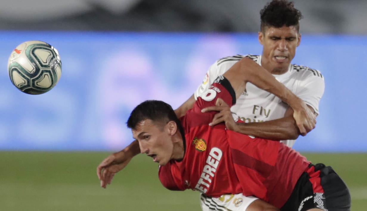 Bek Real Madrid, Raphael Varane, berebut bola dengan pemain Real Mallorca, Ante Budimir, pada laga La Liga di Stadion Alfredo Di Stefano, Kamis (25/6/2020). Real Madrid menang 2-0 atas Real Mallorca. (AP/Bernat Armangue)