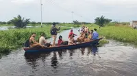 Pihak kecamatan dan Kapolres Rokan Hulu meninjau lokasi banjir di Sontang memakai sampan. (Liputan6.com/M Syukur)