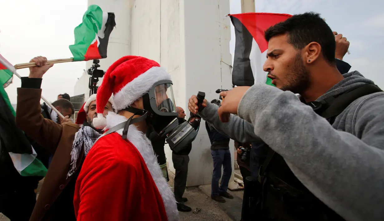 Pengunjuk rasa berkostum Santa Claus berhadapan dengan petugas penjaga perbatasan saat aksi di desa Tepi Barat Bilin dekat Ramallah, Jumat (23/12). Pengunjuk rasa menentang pembangunan tembok pembatas di Israel. (REUTERS/Mussa Issa Qawasma)