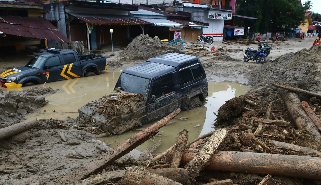 Mobil-mobil terjebak lumpur di daerah yang terkena banjir bandang di Masamba, Sulawesi Selatan, Rabu (15/7/2020). Banjir bandang akibat tingginya curah hujan tersebut mengakibatkan 16 orang meninggal dunia dan puluhan warga dilaporkan masih dalam pencarian. (AP/Khaizuran Muchtamir)