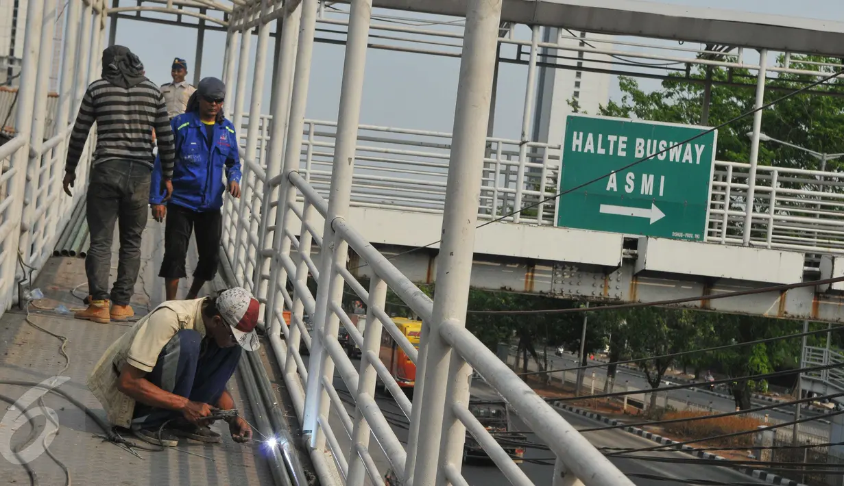 Pekerja menyelesaikan perbaikan Jembatan Penyebrangan Orang (JPO) di Jembatan Asmi, Pulo Gadung, Jakarta, Selasa (3/11/2015). Perbaikan itu dilakukan demi menunjang keselamatan dan kenyamanan pengguna jalan. (Liputan6.com/Gempur M Surya)