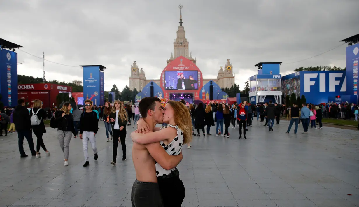 Suporter Rusia berciuman saat berada di Fan Fest Piala Dunia Moskow, Minggu (10/6/2018). Sepenggal kisah romantis saat Piala Dunia 2018 Rusia. (AFP/Dimitar Dilkoff)