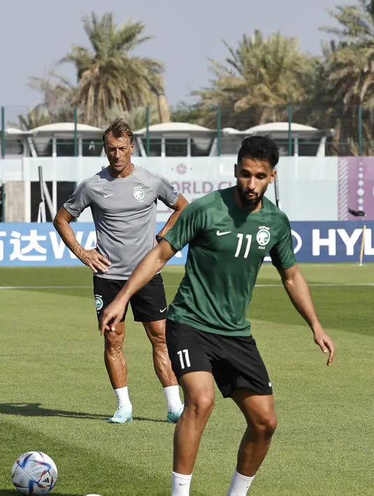 Pelatih Arab Saudi asal Prancis, Herve Renard (kiri) melihat penyerang Saleh Al-Shehri (kanan) mengambil bagian dalam sesi pelatihan di Situs Pelatihan Sealine di Sealine, selatan Doha (21/11/2022). Arab Saudi akan bertanding melawan Argentina pada grup C Piala Dunia 2022 Qatar. (AFP/Khaled Desouki)