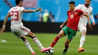 Pemain Maroko Amine Harit berusaha melewati pemain Iran Ramin Rezaeian saat bertanding pada grup B Piala Dunia 2018 di St Petersburg Stadium, Rusia, (15/6). Iran menang tipis 1-0 berkat gol bunuh diri Aziz Bouhaddouz. (AP Photo/Andrew Medichini)