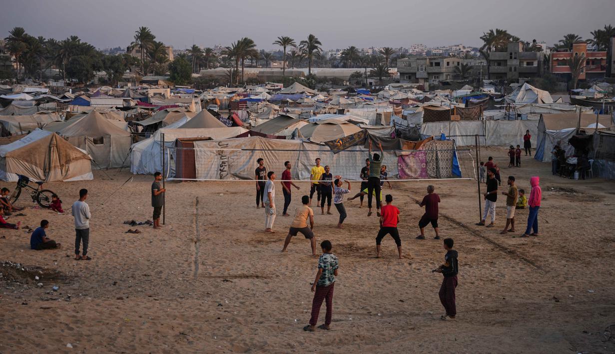 Anak-anak muda Palestina bermain voli di kamp tenda pengungsian di Zawayda, Jalur Gaza tengah, Selasa 4 November 2025. Mereka juga menyerukan kedua pihak agar mematuhi kesepakatan dan mengutamakan keselamatan warga sipil. (AP Photo/Abdel Kareem Hana)