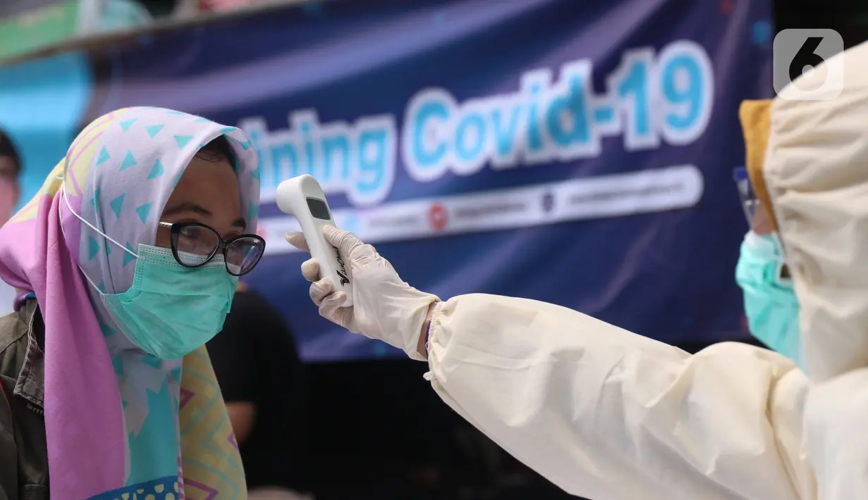 Petugas medis mengecek suhu tubuh warga saat Rapid Test Covid-19  dilakukan oleh Dinkes Provinsi Banten di Tangerang, Selasa (21/4/2020). Warga dapat melakukan isolasi mandiri setelah mengetahui hasil dari Rapid Test Covid-19 tersebut. (Liputan6.com/Angga Yuniar)