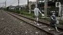 Anak-anak 'Manusia Silver' saat melintasi rel kereta di kawasan Pademangan, Jakarta Utara, Kamis (16/3/2023). (merdeka.com/Iqbal S Nugroho)