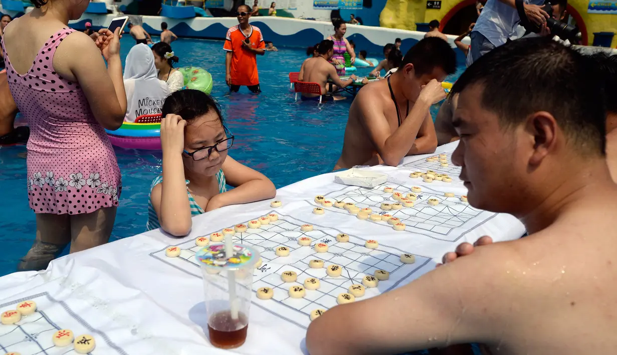Seorang ayah bersama anaknya bermain catur di dalam kolam renang di wilayah Chongqing, Tiongkok, Rabu (2/8). Tiongkok saat ini dilaporkan sedang mengalami cuaca panas dengan suhu di beberapa daerah hampir mencapai 40 derajat celcius. (STR / AFP) 
