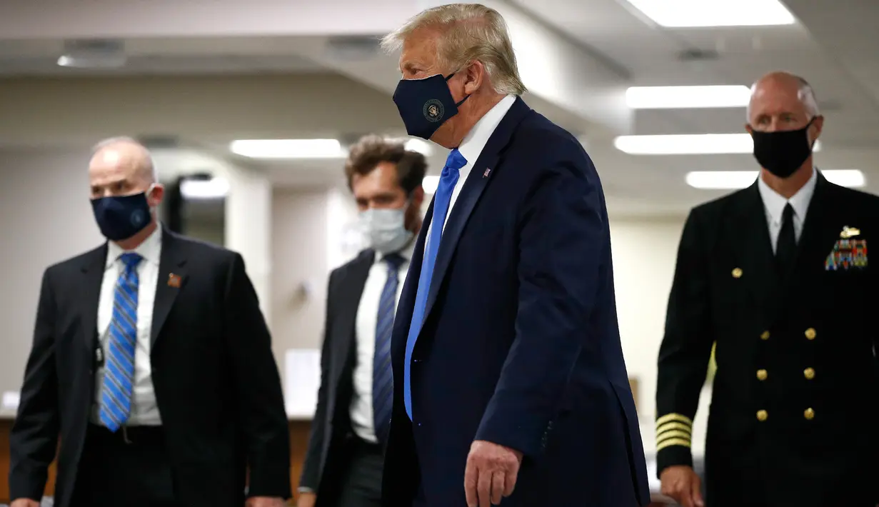 Presiden Amerika Serikat Donald Trump mengenakan masker saat menyusuri lorong dalam kunjungannya ke Pusat Kesehatan Militer Nasional Walter Reed di Bethesda, Maryland, Sabtu (11/7/2020). Trump memakai masker untuk pertama kalinya di depan umum selama pandemi COVID-19. (AP Photo/Patrick Semansky)