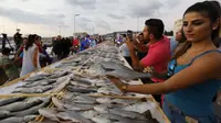 Seorang anggota Lebanon's Batroun Traders Association memegang ikan yang berhasil memecahkan rekor makanan laut terbanyak di daerah kota pantai Batroun, Minggu (4/9). Menurut panitia, total ikan yang dikumpul sebanyak 2 ton 614 kg. (AFP PHOTO/Anwar AMRO)