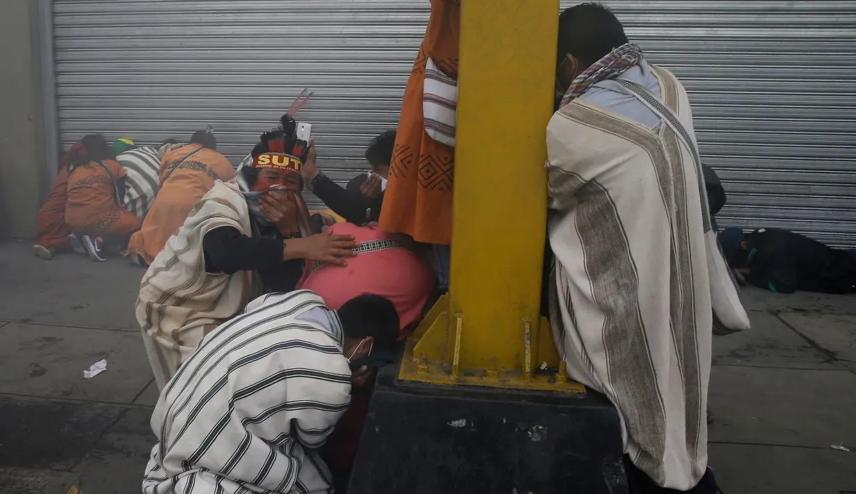 Sejumlah guru yang bekerja di Amazon Peru berlindung dari gas air mata dan peluru karet saat bentrok dengan polisi di Lima, Peru, (24/8). Para guru meminta pemerintah mengalokasikan lebih banyak dana ke sektor pendidikan. (AP Photo / Martin Mejia)