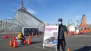 Seorang petugas kesehatan menampilkan papan di pusat vaksinasi Covid-19 skala besar yang didirikan di Six Flags Magic Mountain di Valencia, California, Selasa (2/2/2021). Situs ini di salah satu dari lima situs vaksin corona utama yang dioperasikan oleh Los Angeles County. (VALERIE MACON/AFP)