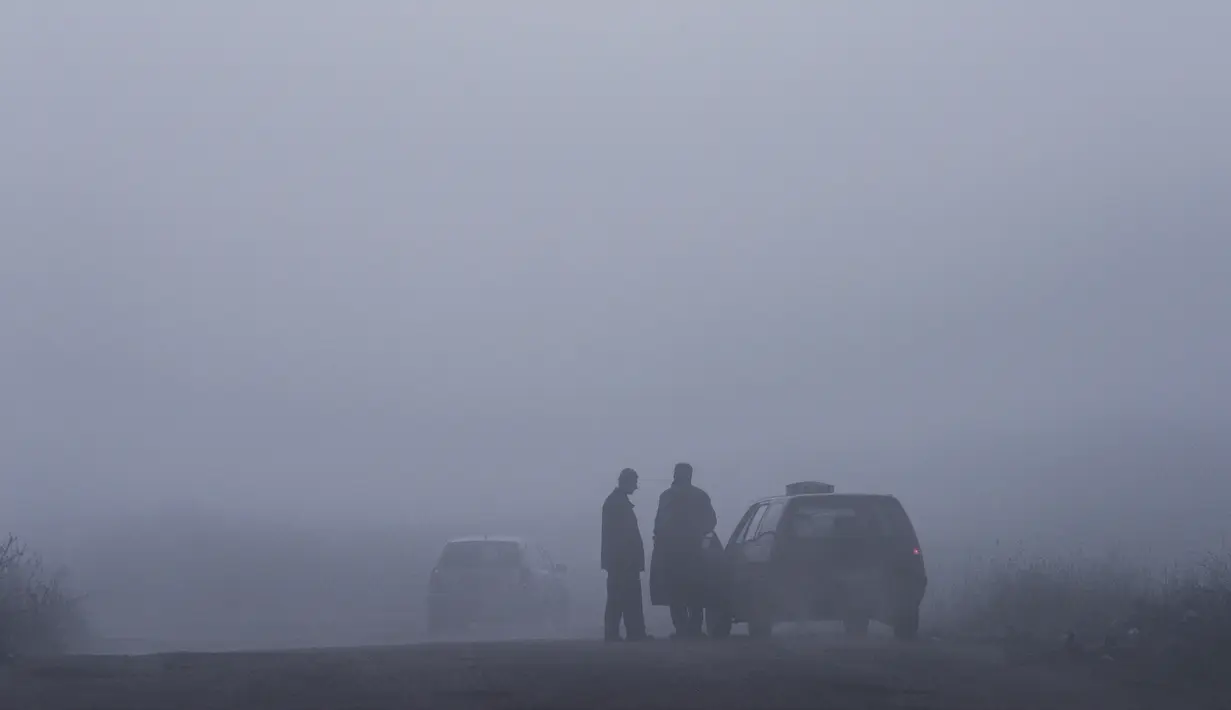 Seorang pengemudi taksi berbincang saat kabut tebal melanda kota Pristina (18/12/2019). Pristina dan banyak kota lain di Kosovo mengalami polusi udara tingkat tinggi. (AFP/Armend Nimani)