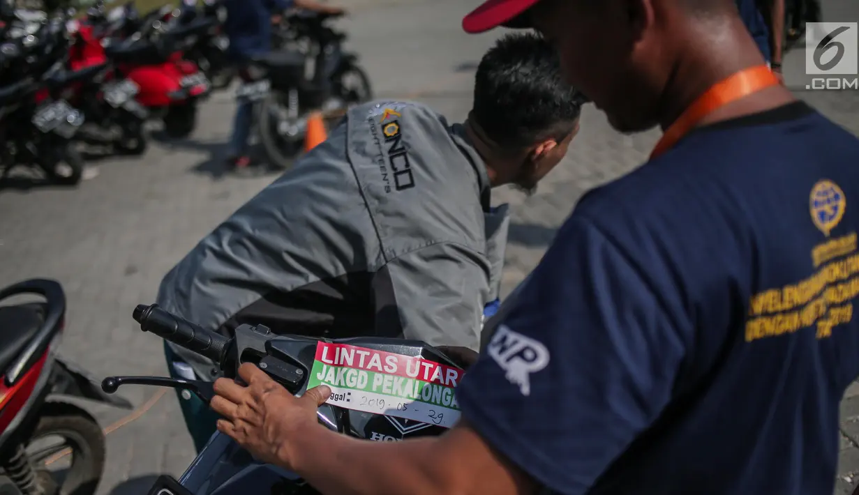 Pekerja menempelkan stiker pada motor pemudik sebelum dikirim dengan kereta api di Stasiun Jakarta Gudang, Selasa (28/5/2019). Direktorat Lalu Lintas dan Angkutan Kereta Api Kementerian Perhubungan mengangkut 18.096 motor pemudik secara gratis pada mudik Lebaran 2019. (Liputan6.com/Faizal Fanani)