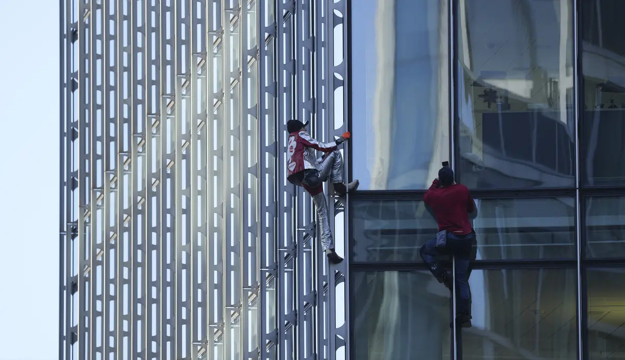 Alain Robert yang dikenal sebagai 'Spiderman Prancis' (kiri) dan Leo Urban memanjat gedung pencakar langit Skyper di pusat Frankfurt, Jerman, 23 November 2021. Alain Robert memanjat gedung setinggi 153 meter itu untuk meningkatkan kesadaran dunia tentang perubahan iklim. (AP Photo/Michael Probst)