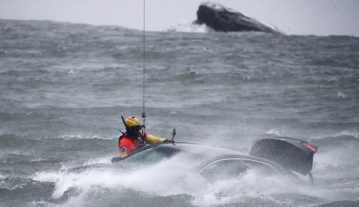Penyelam Penjaga Pantai AS diturunkan dari helikopter untuk menarik tubuh pengendara mobil yang terjebak dalam arus deras di tepi Air Terjun Niagara, New York, AS, 8 Desember 2021. Mobil tersebut tersangkut pada bebatuan dekat tepi Air Terjun Niagara. (AP Photo/ Jeffrey T. Barnes)