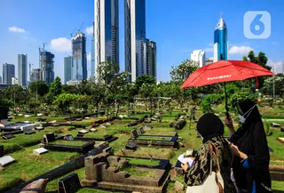 Warga melintas di antara makam di TPU Karet Bivak, Jakarta, Selasa (11/5/2021). Pemprov DKI akan memberlakukan larangan ziarah kubur Idulfitri di seluruh TPU mulai 12 hingga 16 Mei untuk mencegah terjadinya penyebaran Covid-19 saat berkumpul untuk berziarah. (Liputan6.com/JohanTallo)