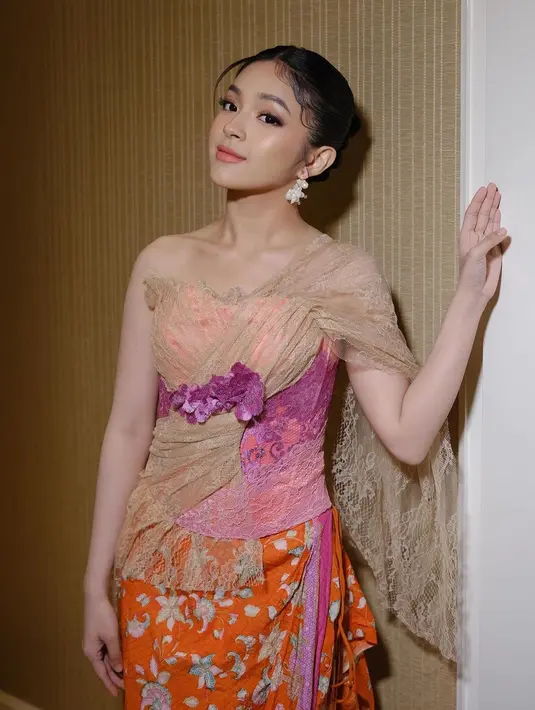 Eca Aura tampil super cantik mengenakan outfitnya yang terdiri dari atasan tanpa lengan dengan bahan brokat menyerupai kebaya, bernuansa cokelat dengan bustier pink dan ungu. [Foto: Instagram/elsaajapasal]