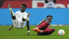 Penyerang Bayern Munchen, Alphonso Davies dan bek  Bayer Leverkusen Jeremie Frimpong terjatuh saat bertabrakan pada laga pekan ke-25 Liga Jerman 2022/2023 di Stadion BayArena, Senin (20/3/2023) dini hari WIB. (AP Photo/Martin Meissner)