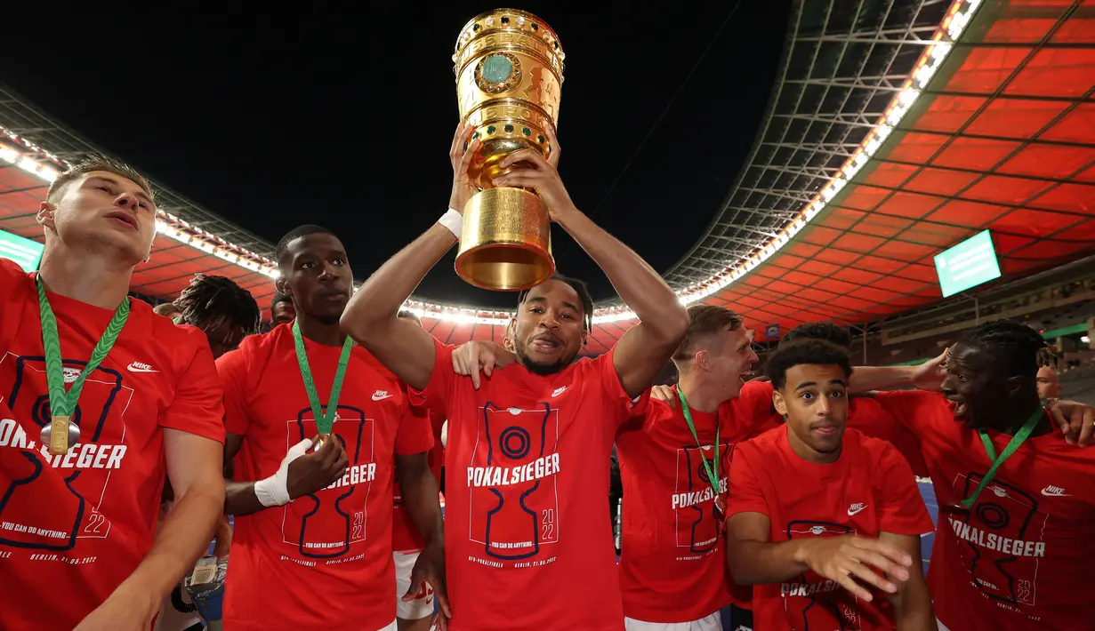 Pemain Leipzig, Christoper Nkunku (tengah) merayakan kemenangan dengan mengangkat trofi DFB Pokal atau Piala Liga Jerman bersama rekan setimnya usai mengalahkan SC Freiburg pada partai final yang berlangsung di Stadion Olimpiade di Berlin, Jerman, Sabtu, 21 Mei 2022 waktu setempat. Die Bullen berhasil menang lewat babak adu penalti dengan skor 4-2 usai laga berjalan imbang 1-1. (AFP/Ronny Hartmann)