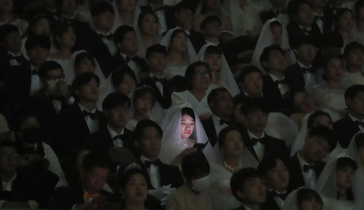 Pengantin wanita bermain smartphone-nya dalam upacara pernikahan massal di Cheong Shim Peace World Center, Gapyeong, Korea Selatan, Jumat, (7/2/2020). Wabah virus corona yang melanda sejumlah wilayah di dunia tidak menghalangi antusias warga Korsel mengikuti acara itu. (AP Photo/Ahn Young-joon)