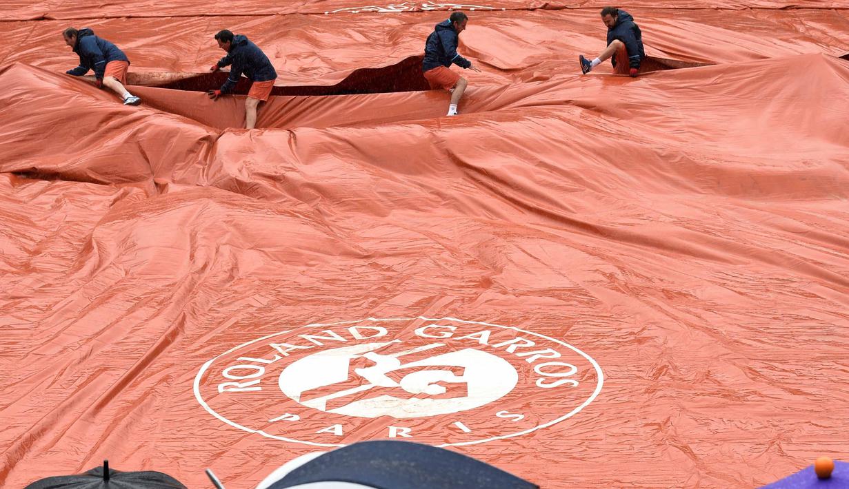 Para petugas menutup lapangan Roland Garros saat turun hujan pada turnamen Prancis Terbuka 2016 di Roland Garros, (28/5/2016). (AFP/Miguel Medina)