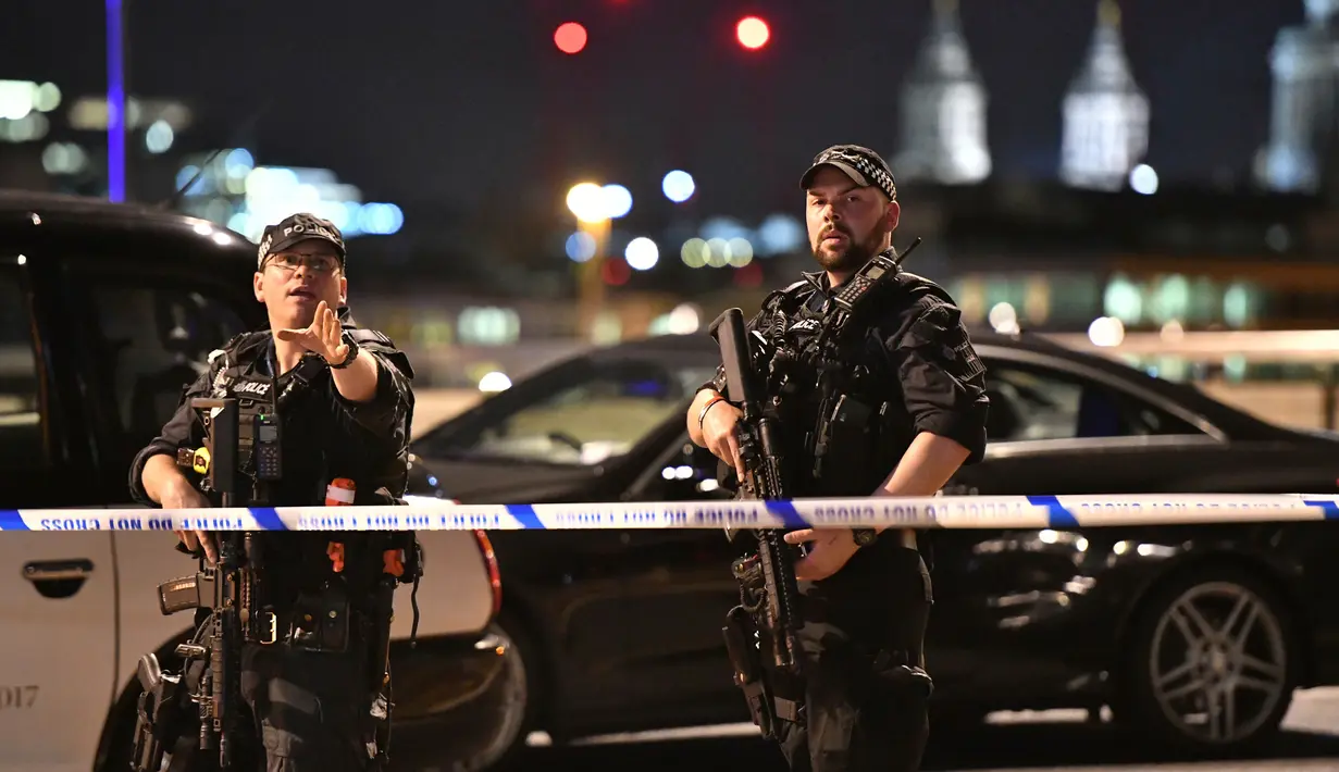 Dua polisi bersenjata memblokade kawasan London Bridge, setelah serangan teror, Sabtu (3/6). Serangan teror terjadi di London Bridge dan Borough Market, yang dilakukan lima orang pria dan menewaskan 6 orang termasuk pelaku. (Dominic Lipinski/PA via AP)