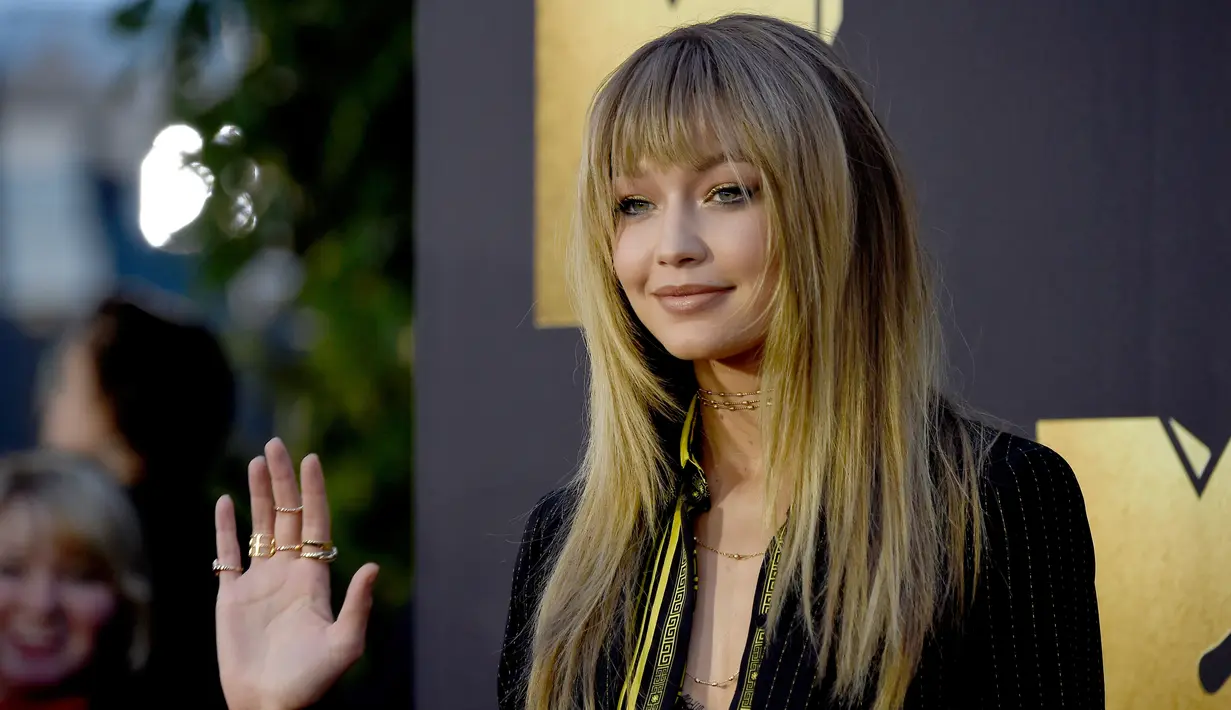 Gigi Hadid melambaikan tangan ke arah fotografer tiba di acara MTV Movie Awards di Warner Bros Studio, Burbank, California, Sabtu (9/4).  Kekasih Zayn Malik itu mengubah gaya rambutnya dengan tampil berponi (Frazer HARRISON/GETTY IMAGES NORTH AMERICA/AFP)