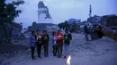 Sejumlah Orang berpose membawa lilin di depan reruntuhan Menara Dharahara untuk menghormati para korban gempa Nepal di Kathmandu, Nepal, (7/5/2015). Gempa berkekuatan 7,8 yang meluluhlantakkan Nepal pada 25 April 2015 lalu. (REUTERS/Navesh Chitrakar)