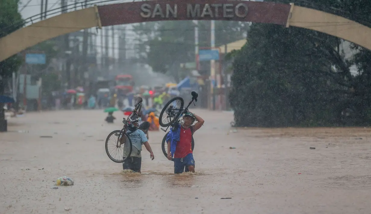 Sejumlah warga berjalan menembus genangan banjir yang diakibatkan oleh Topan Vamco di Provinsi Rizal, Filipina (12/11/2020). Topan Vamco membawa angin kencang dan hujan deras yang memicu tanah longsor, longsor batu, serta banjir bandang. (Xinhua/Rouelle Umali)