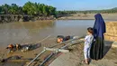 Dan, TNI AD, mulai Januari 2026, menargetkan pembangunan sekitar 50 jembatan darurat (Bailey), di Aceh dan wilayah lain yang terdampak, untuk menggantikan penyeberangan tali yang berisiko tinggi. Tampak dalam foto, seorang wanita dan anaknya melihat orang-orang menggunakan rakit tali penyeberangan untuk menyeberangi Sungai Peusangan setelah banjir bandang yang menghancurkan desa-desa di sekitarnya di Kabupaten Bireuen, provinsi Aceh, pada Senin 5 Januari 2026. (CHAIDEER MAHYUDDIN/AFP)