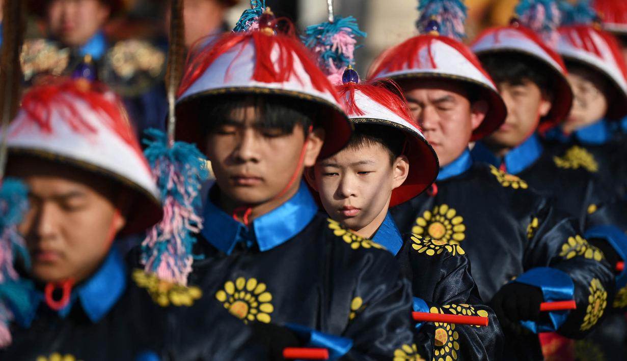 Para pemain yang berpakaian seperti penjaga kekaisaran mengambil bagian dalam pertunjukan ulang upacara pengorbanan di pameran kuil taman Ditan pada hari kedua Tahun Baru Imlek Naga di Beijing pada 11 Februari 2024. (GREG BAKER/AFP)