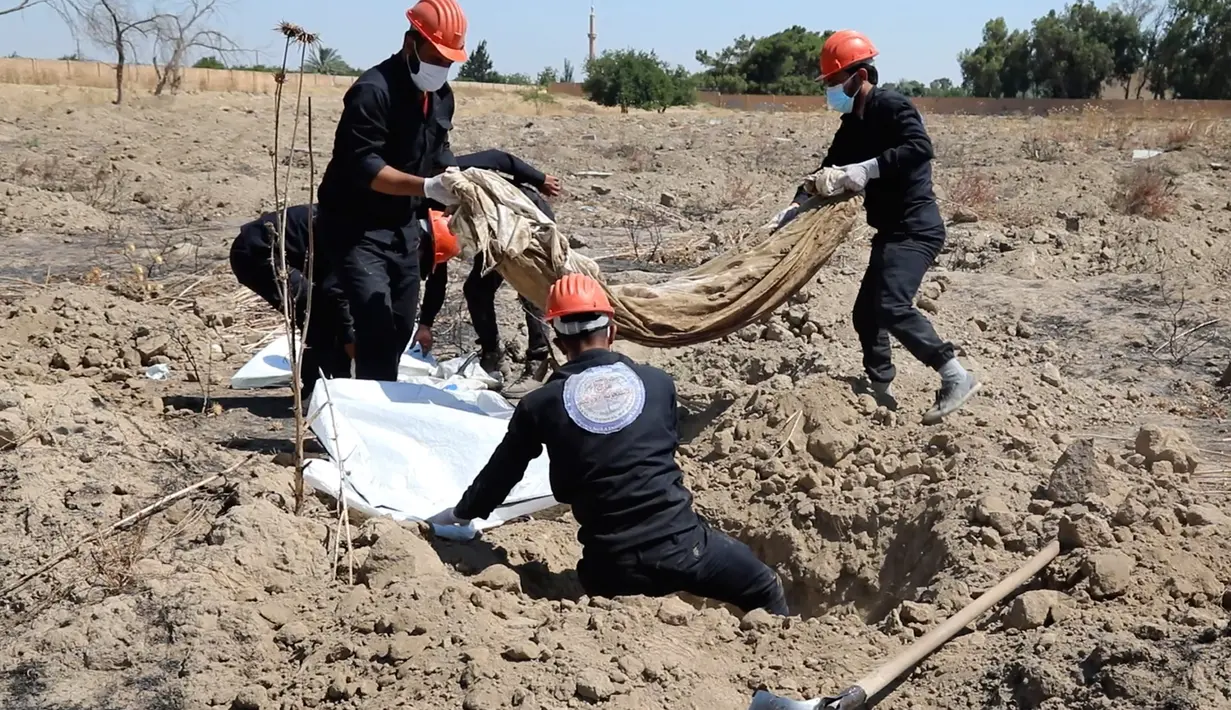 Pekerja Dewan Sipil Raqqa memindahkan tulang belulang manusia di kuburan massal yang ditemukan di Raqqa, Suriah, 14 Juli 2019. Di antara jasad-jasad yang ditemukan merupakan warga sipil termasuk perempuan dan anak-anak, diyakini merupakan  orang-orang yang telah ditembak mati militan ISIS (AP Photo)